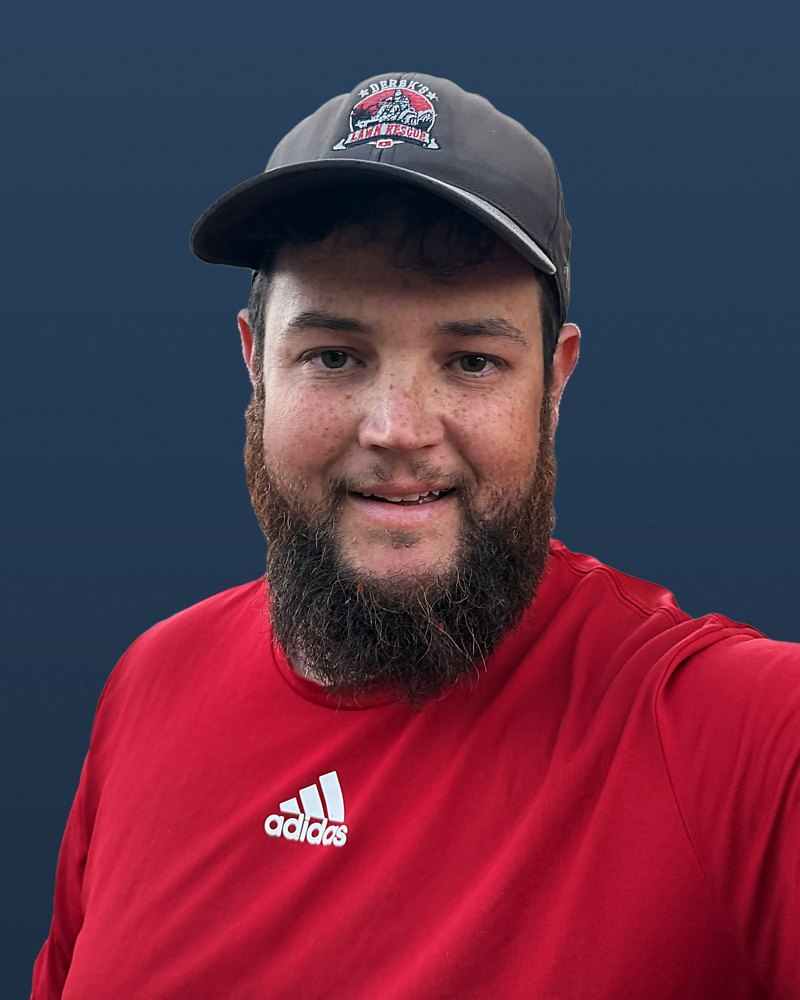 Derek smiling in his red work shirt and cap